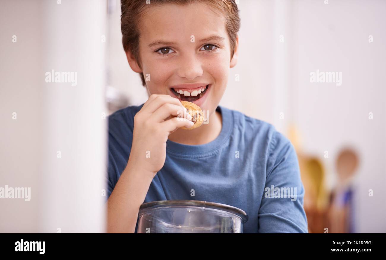 Yum yum. A young boy eating a cookie while holding a cookie jar. Stock Photo