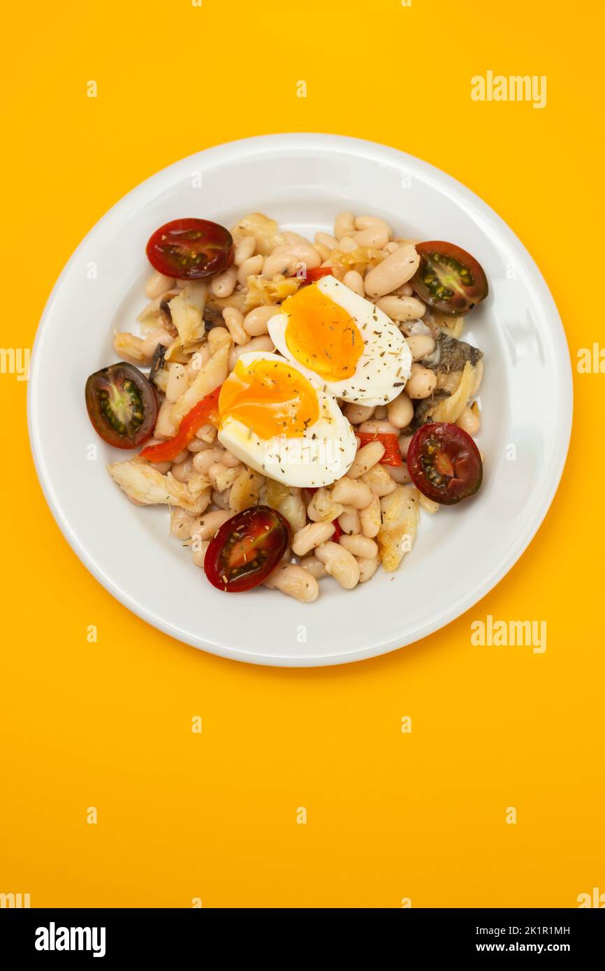 Salad with Fried cod fish and white beans on the plate. Stock Photo