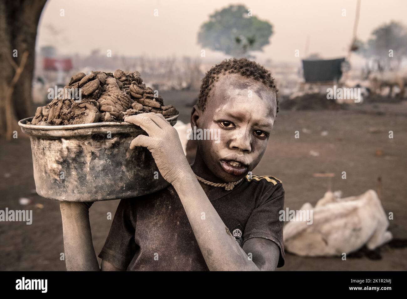 A child carrying leather to put on the fire. South Sudan: THESE STUNNING images show the incredible bond between the Mundari people and their cattle i Stock Photo
