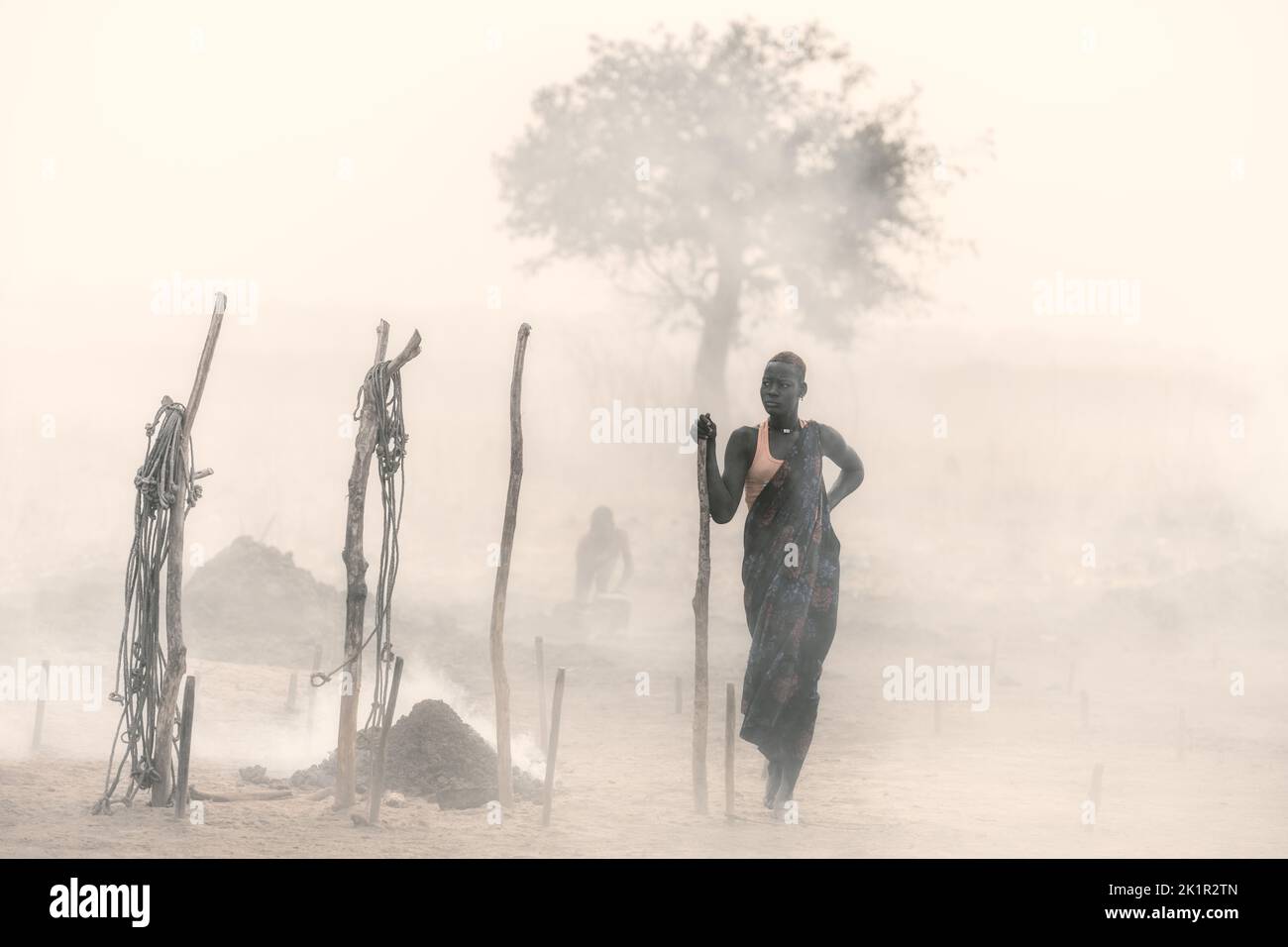 A woman waiting to tether the cattle. South Sudan: THESE STUNNING images show the incredible bond between the Mundari people and their cattle in South Stock Photo