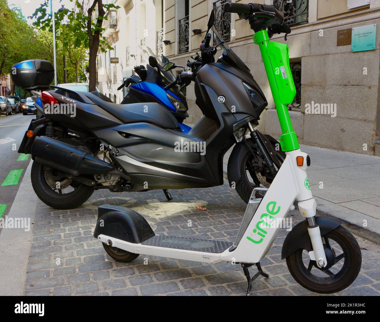 Lime escooter parked in a street next to motorbikes in Madrid Spain