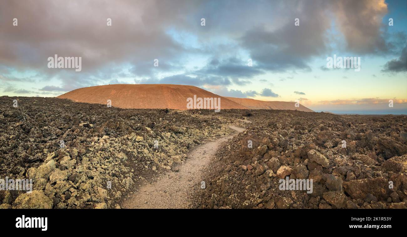 Volcanic landscape near Mancha Blanca looking to the Caldera Blanca on the island of Lanzarote shortly after sunrise. Stock Photo