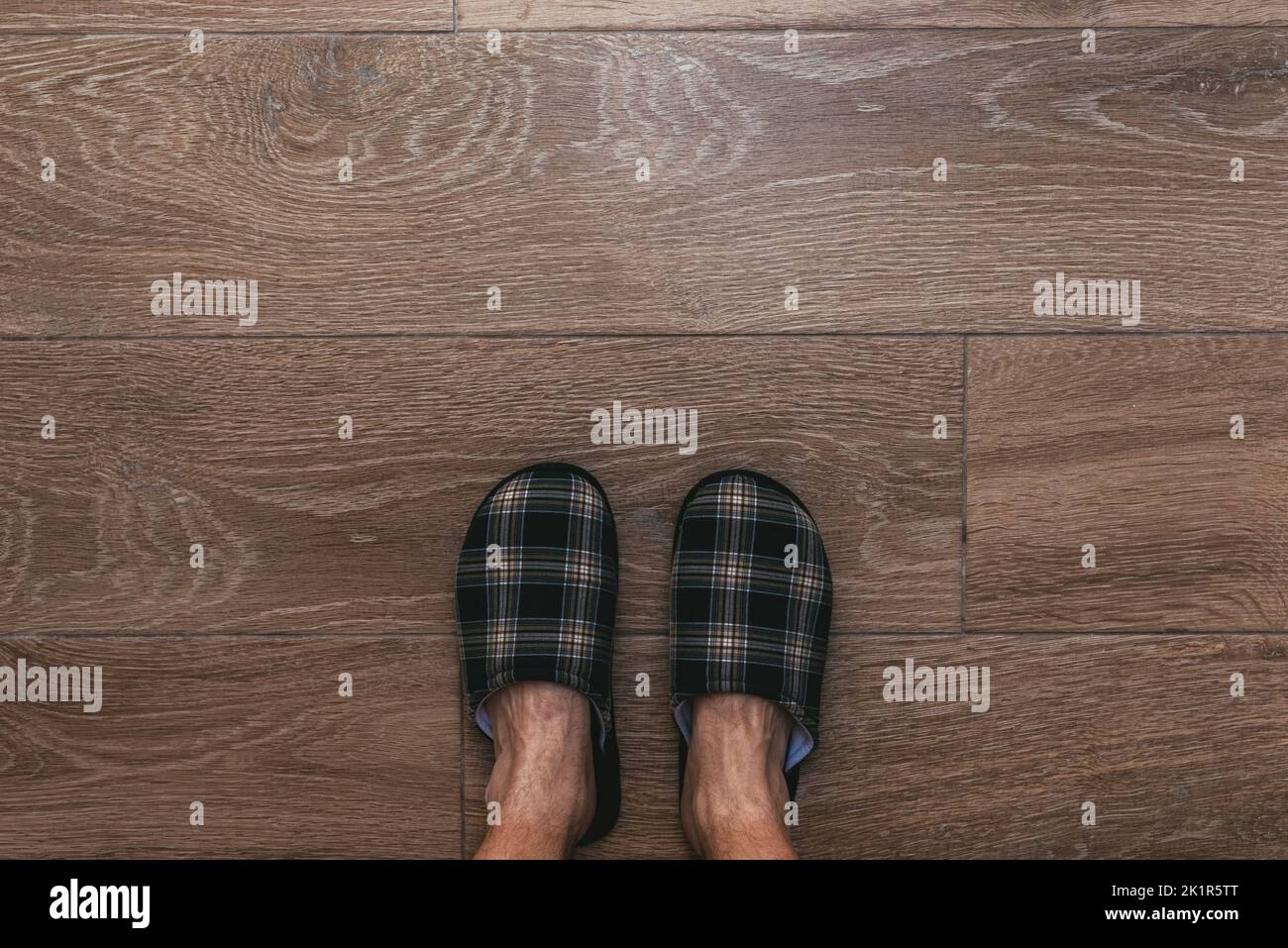 Man wearing home slippers standing on the bathroom floor tiles, top down perspective, copy space included Stock Photo