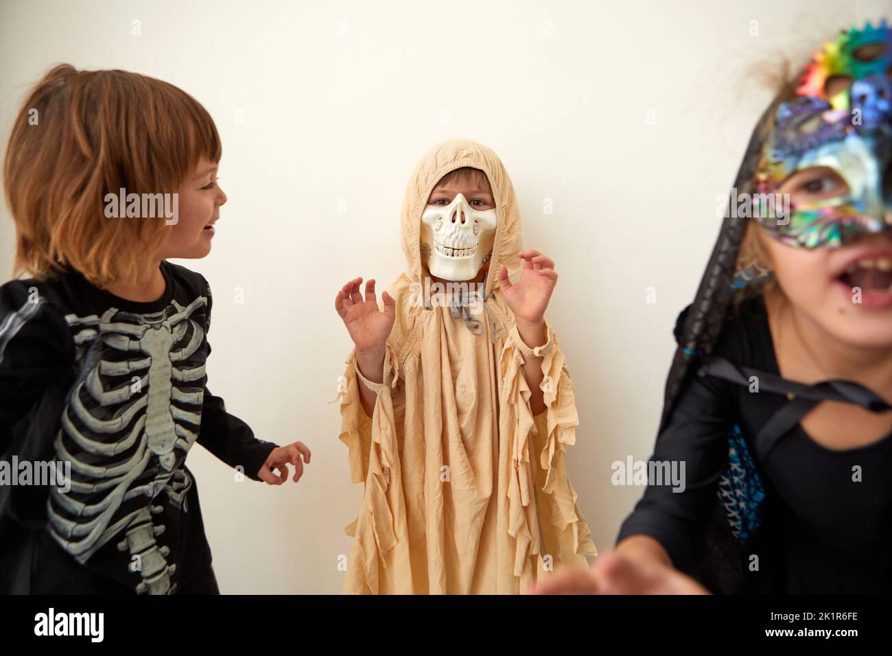 Children trick or treating on Halloween party, different costumes ghost, skeleton witch on white background Stock Photo