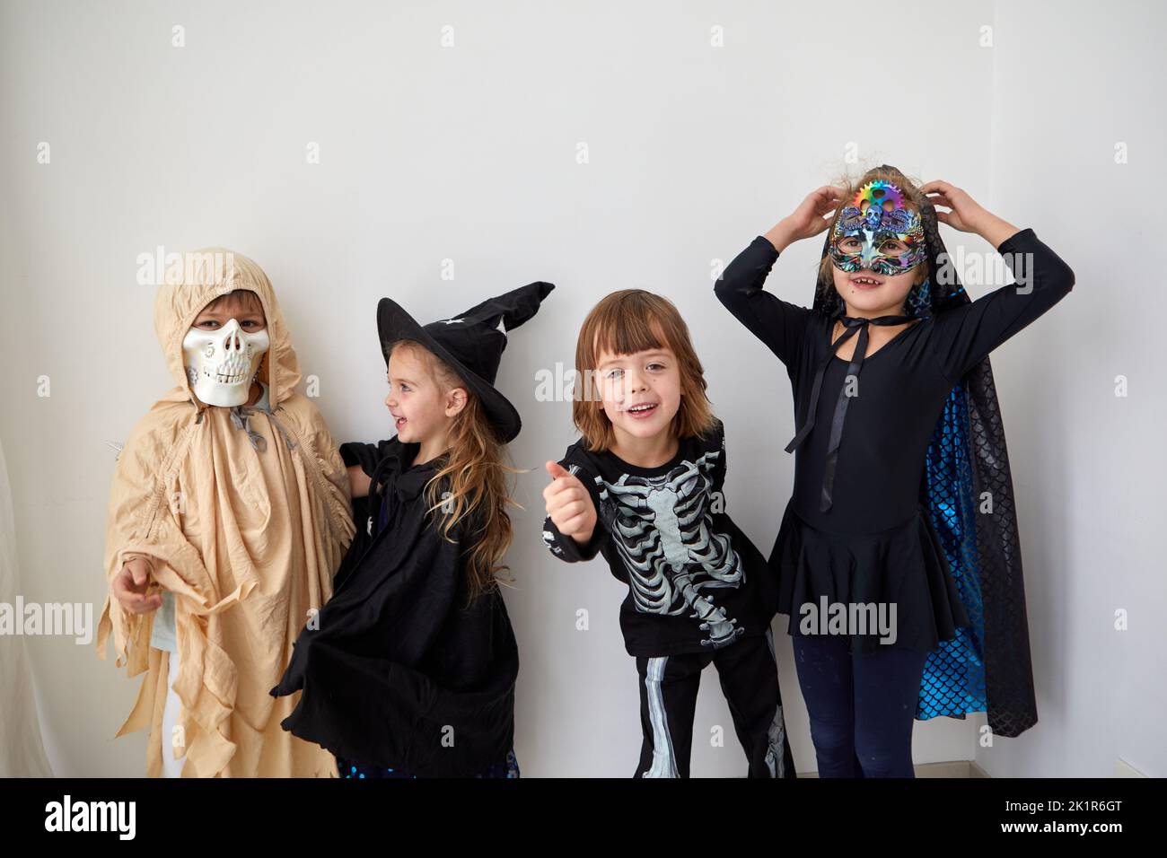 Group of happy children wearing creative Halloween costumes looking at camera on white background in studio Stock Photo