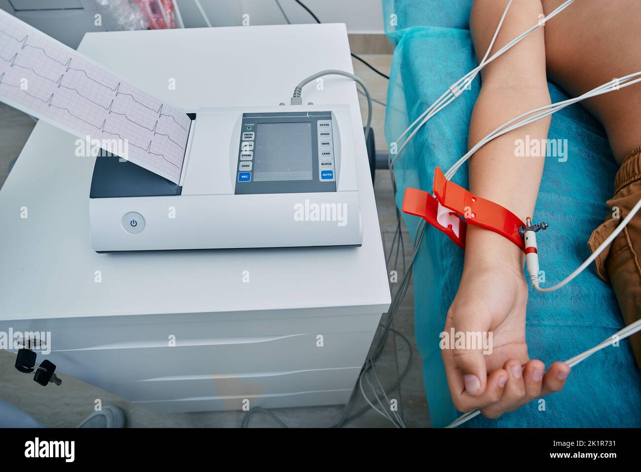 Heart electrocardiography for children. Cardiograph with ECG printout for child patient lying in medical bed with vacuum sensors Stock Photo