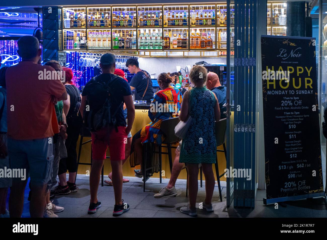 Happy Hour sign and group of customers outside bar on sidewalk at