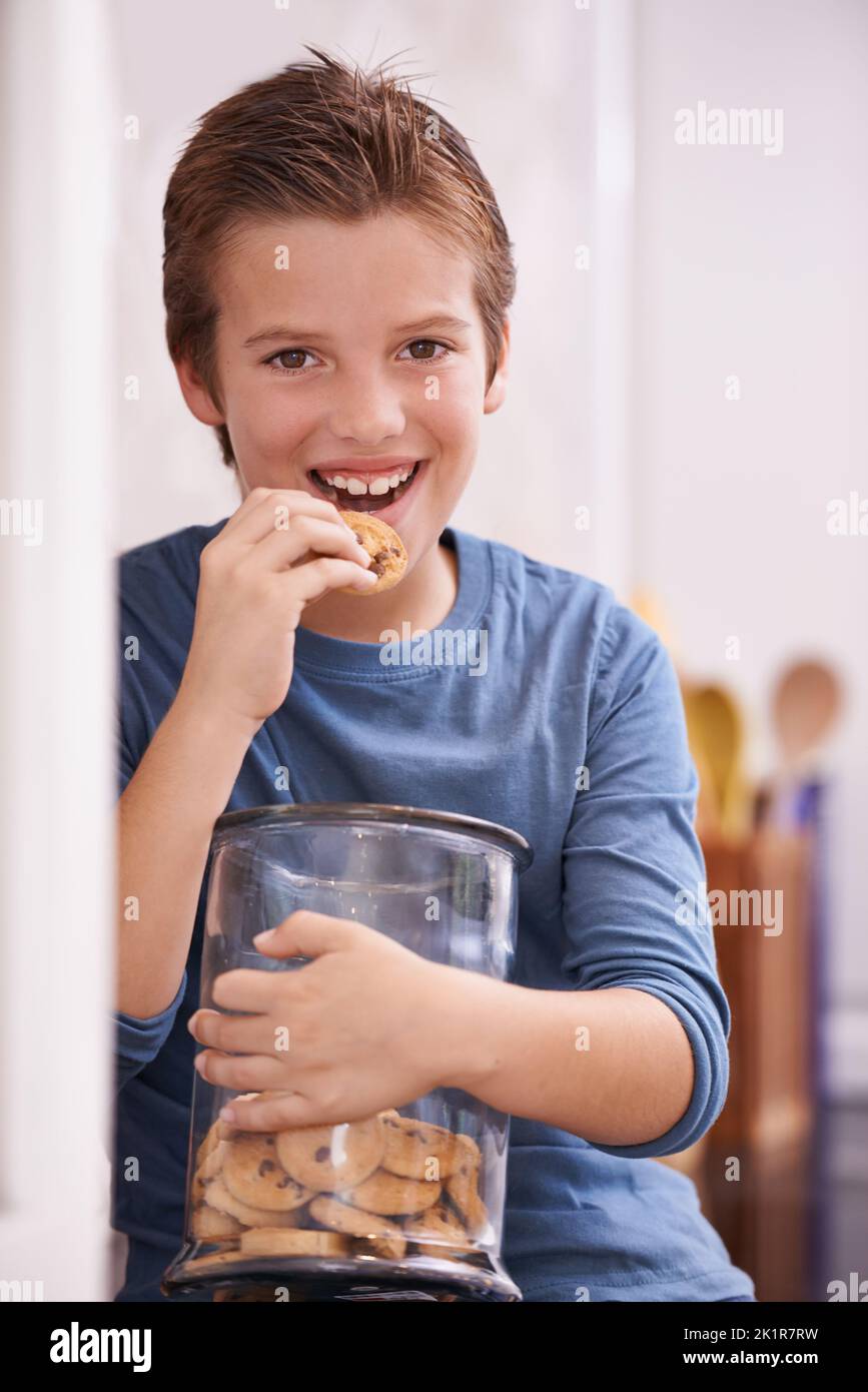All for me. A young boy eating a cookie while holding a cookie jar. Stock Photo