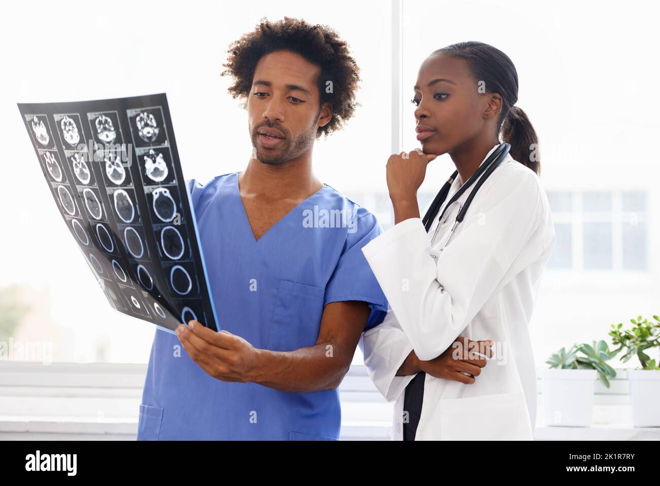 The scans will help them with a diagnosis. a female doctor and male nurse studying a CAT scan. Stock Photo