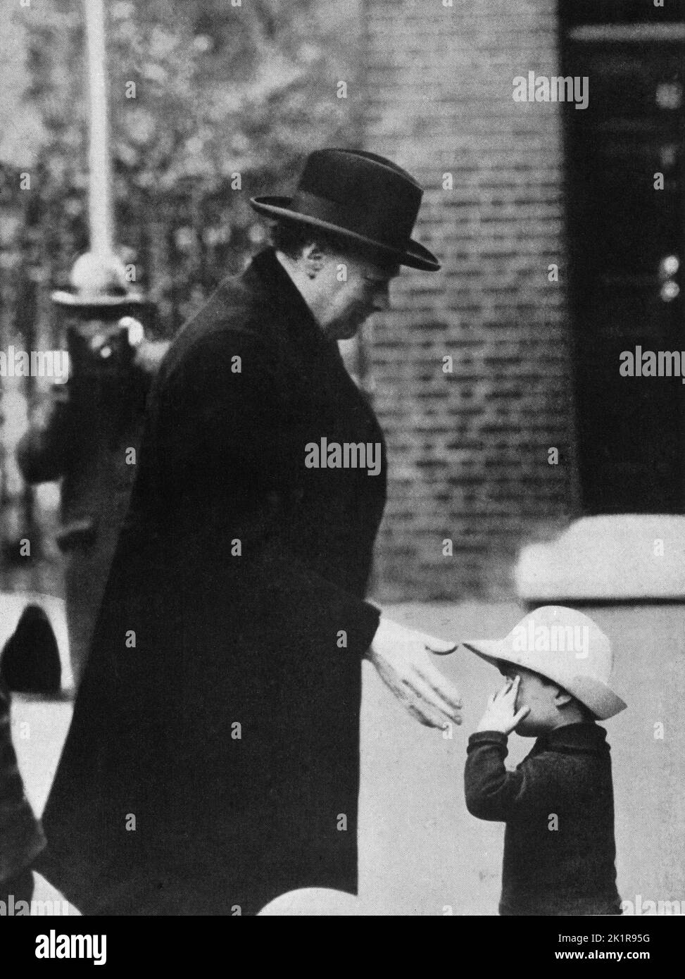 Winston Churchill greets a small child on his way to attend a Cabinet meeting at the time of the General Strike. 1926. Stock Photo