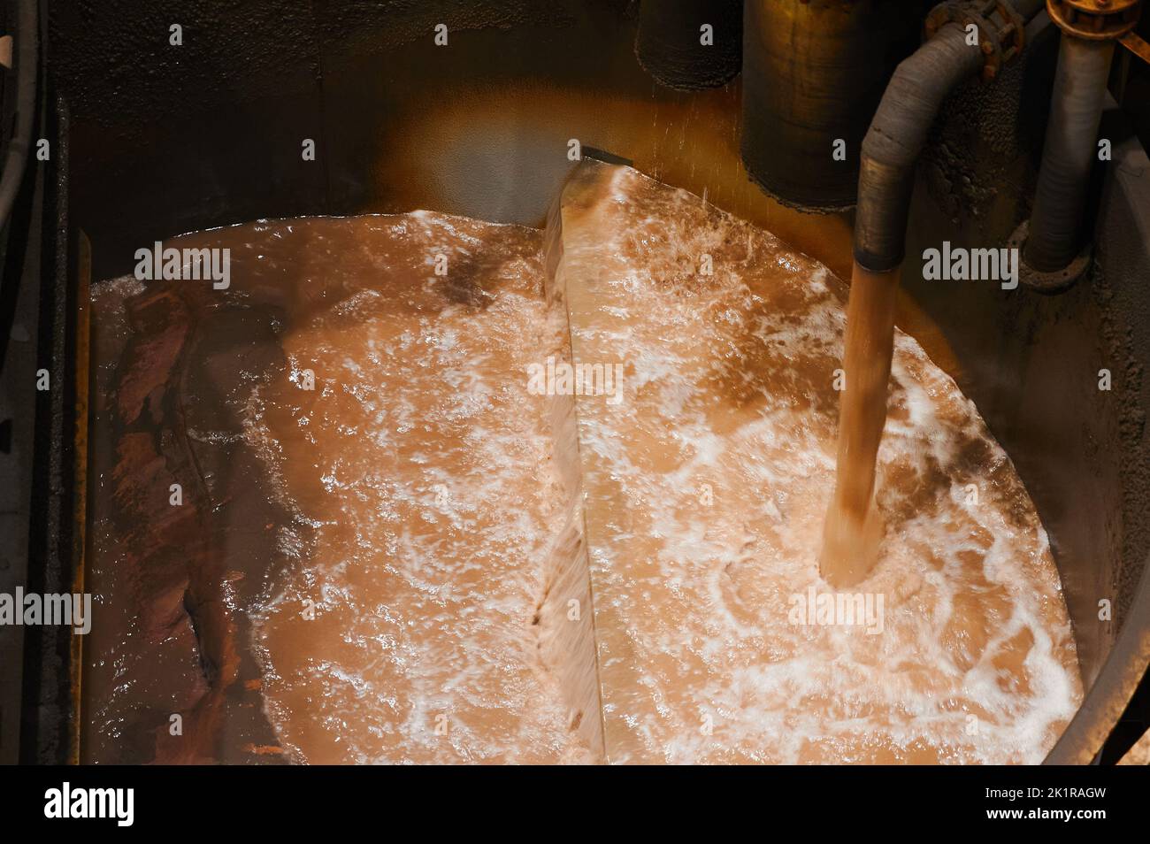 Pouring liquid into huge bath of modern floatation machine Stock Photo