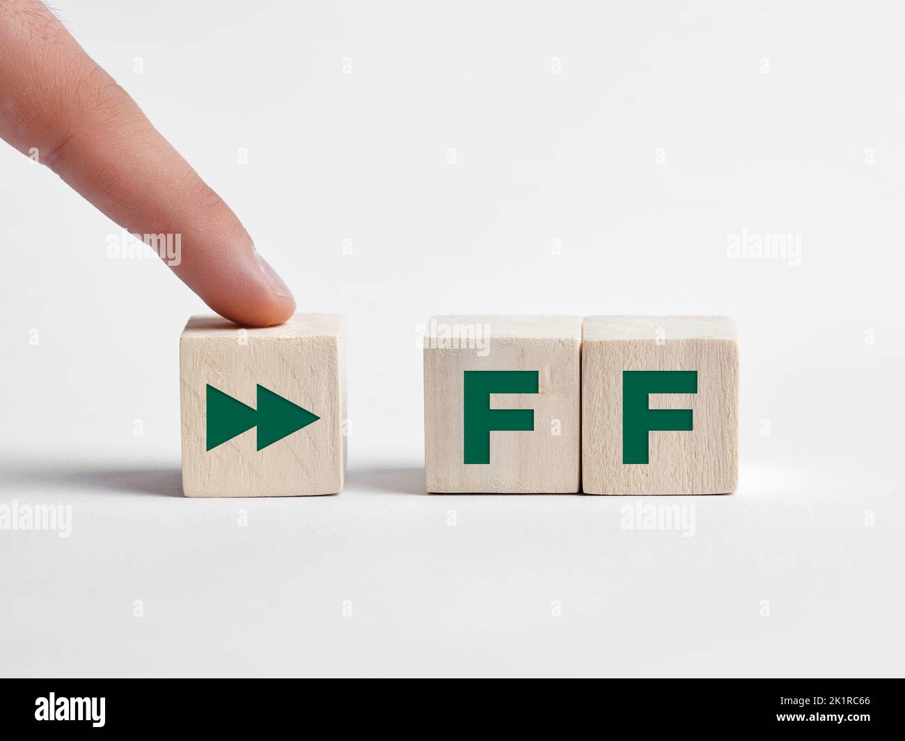 Finger presses the fast forward FF button on wooden cubes. Stock Photo