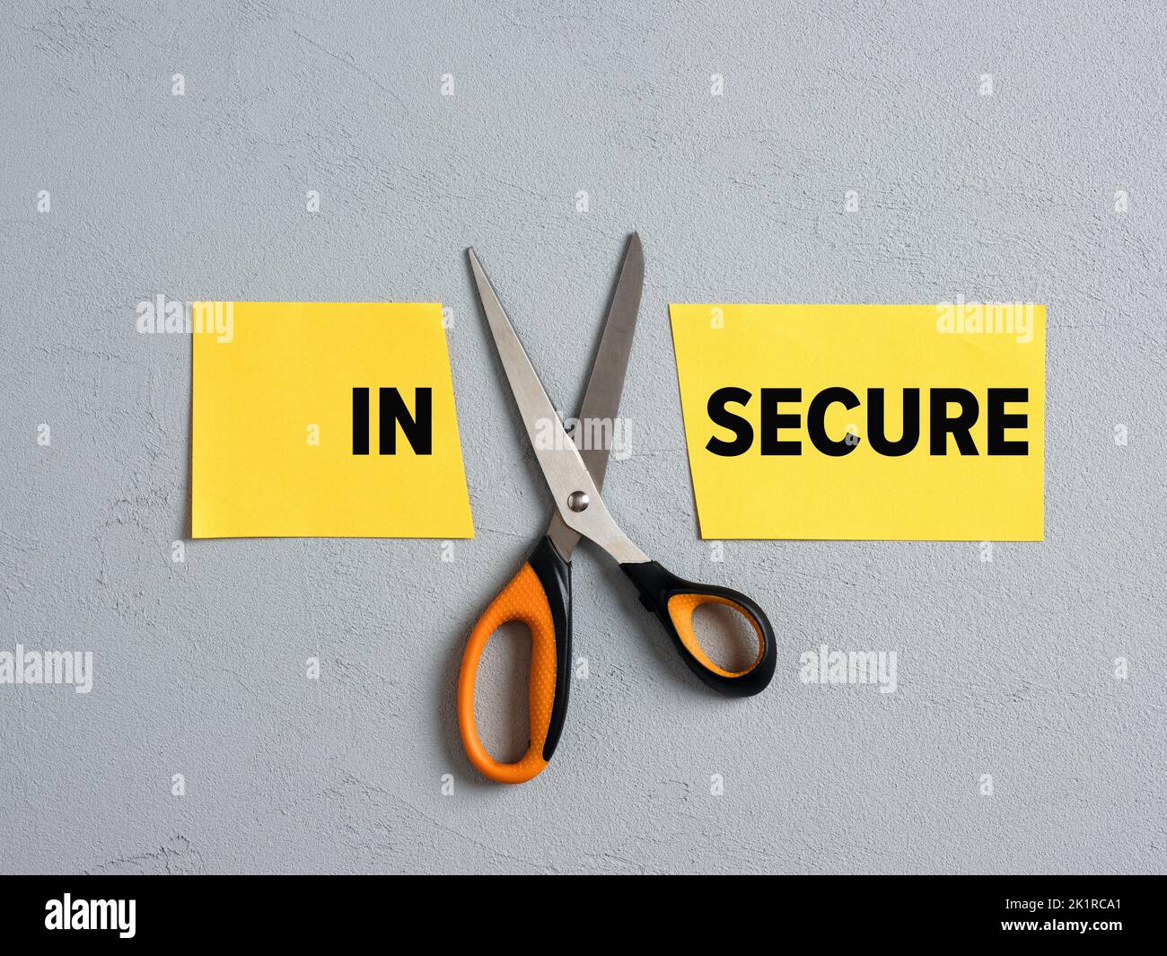 Scissors Cutting off the word insecure and transforming into secure. Security, insurance, confidence, protection and overcoming fears concept. Stock Photo