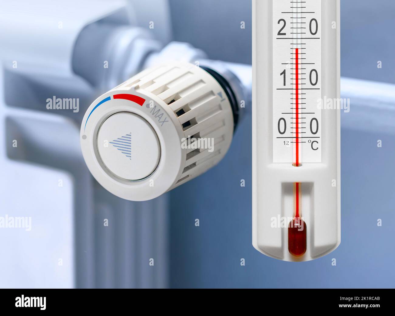 Heating radiator thermostat set to low temperature and room thermometer for saving money at heating costs. Energy crisis, energy efficiency and rising Stock Photo