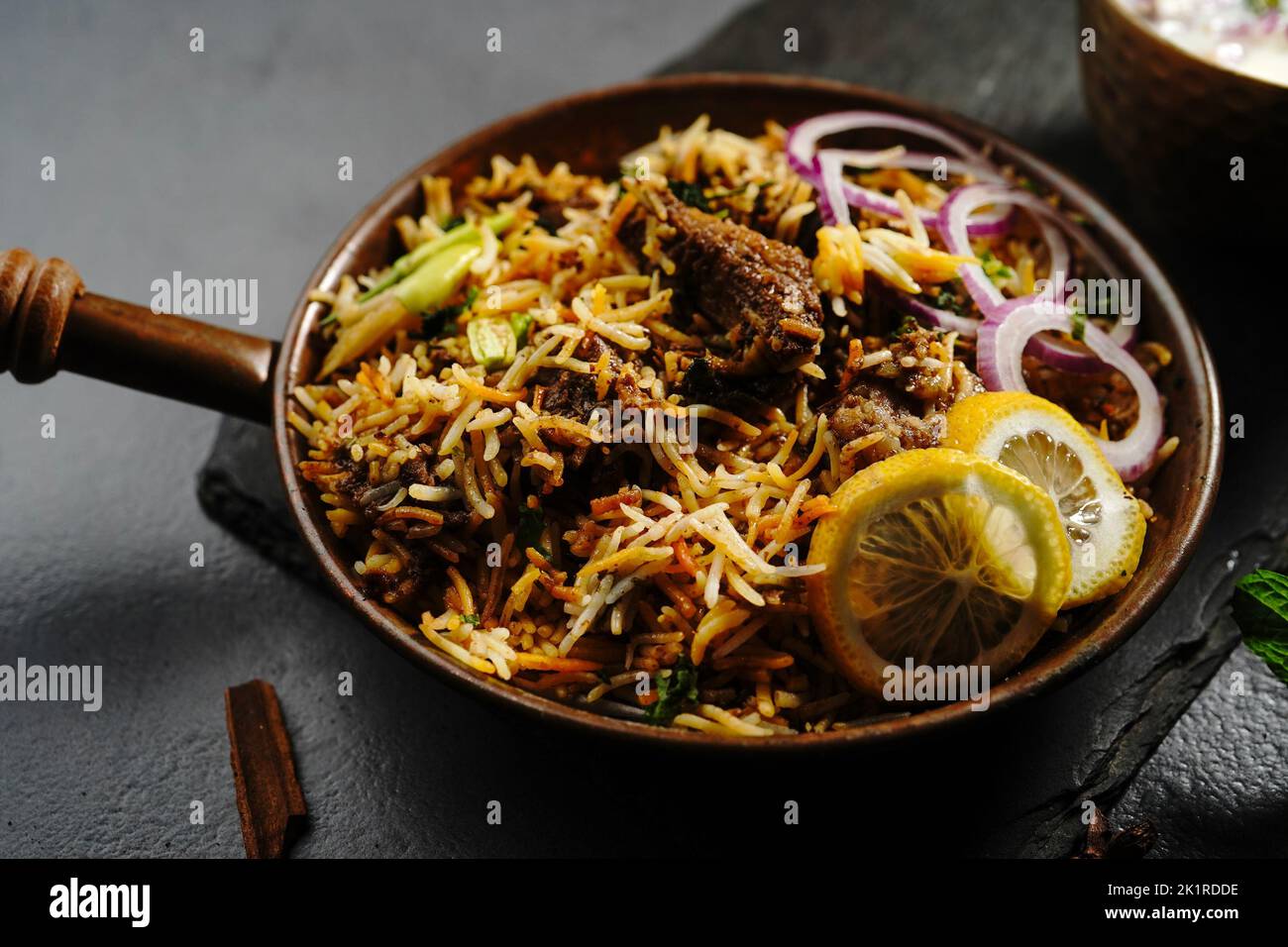 Hyderabadi Mutton goat biryani served with yogurt raita on moody