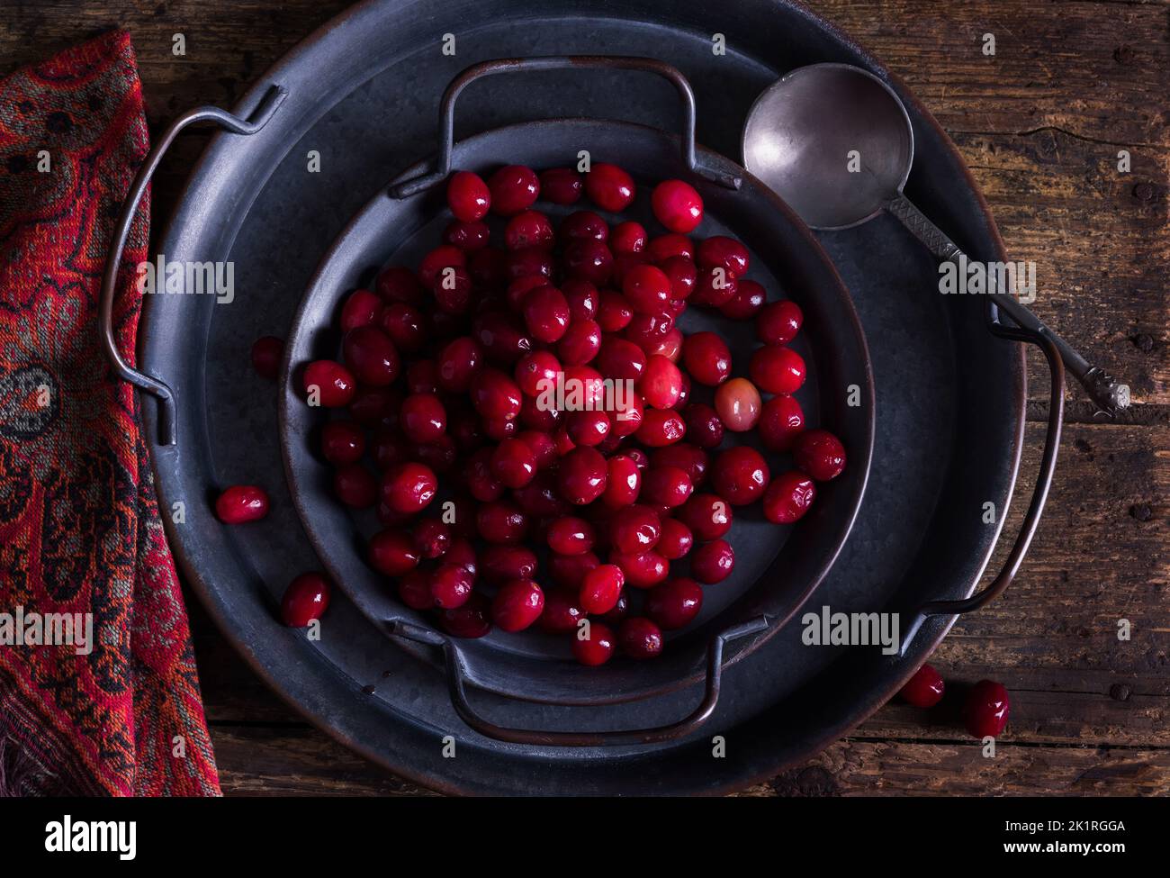 Still life with 2 rustic plates filled with fresh cranberries on an antique wooden table Stock Photo
