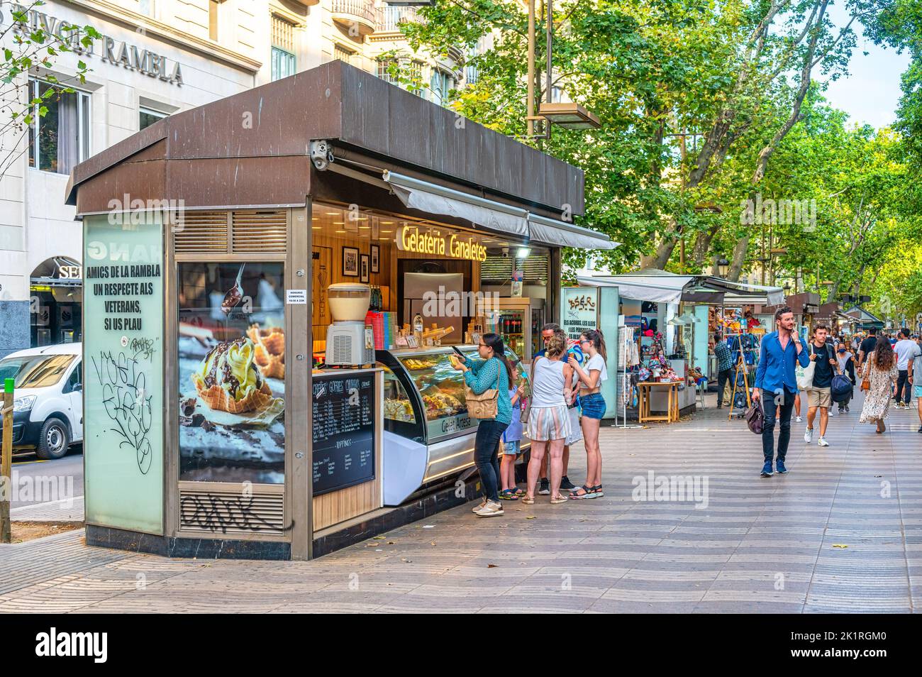 People buy food in a kiosk set in La Rambla. Tourists also walk in the scene. Stock Photo