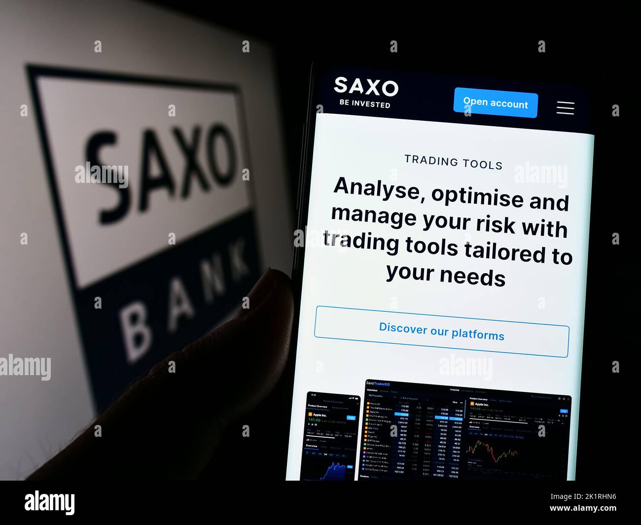 Person holding smartphone with webpage of Danish investment banking company Saxo Bank AS on screen with logo. Focus on center of phone display. Stock Photo