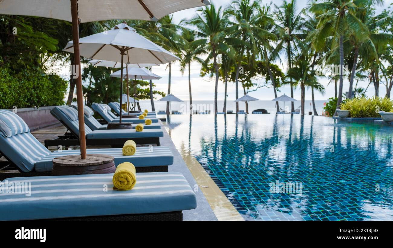 tropical pool with palm trees and beach bed chairs at a luxury resort ...