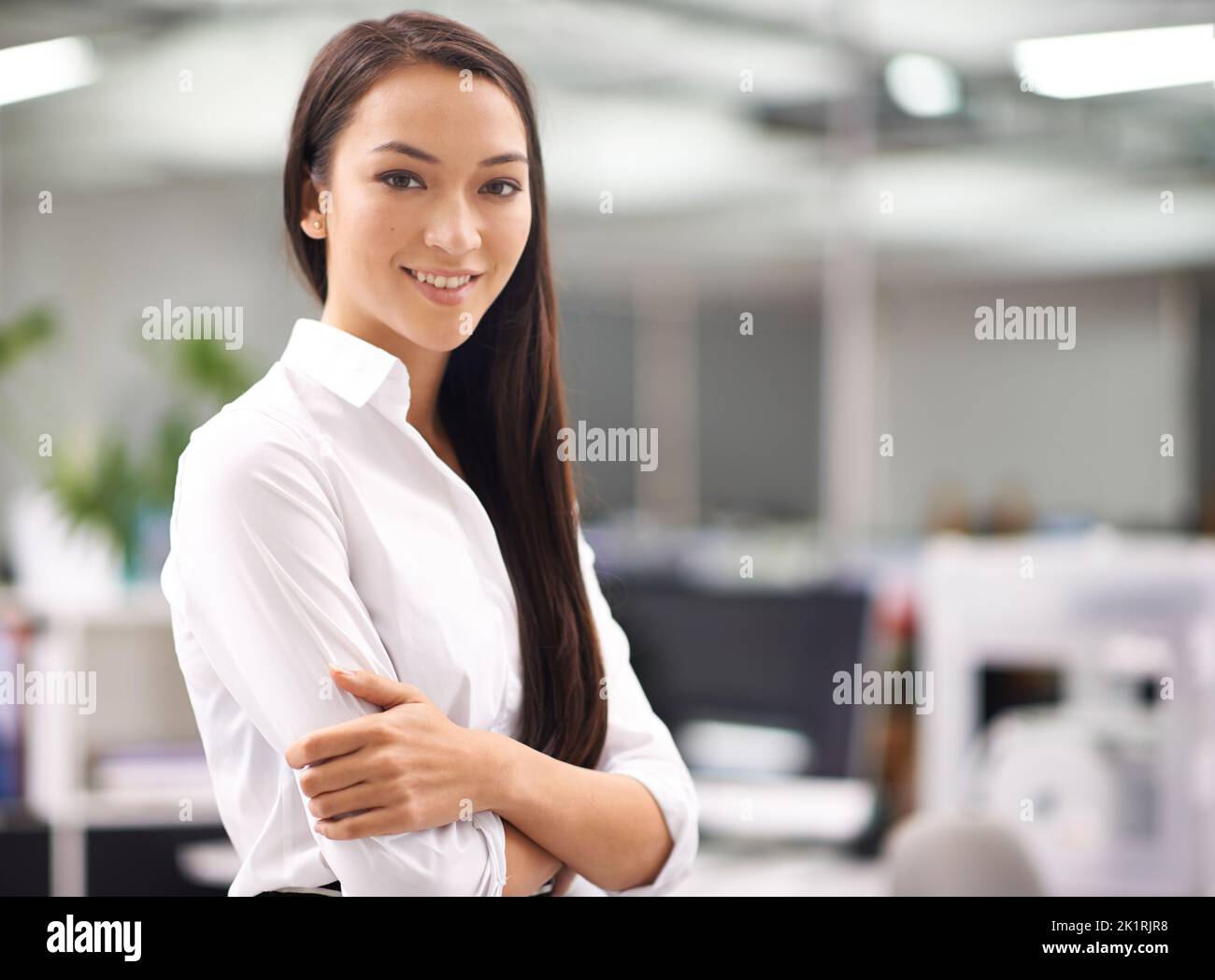 Theres no misplaced confidence here. Portrait of an attractive young businesswoman standing with her arms folded in the office. Stock Photo