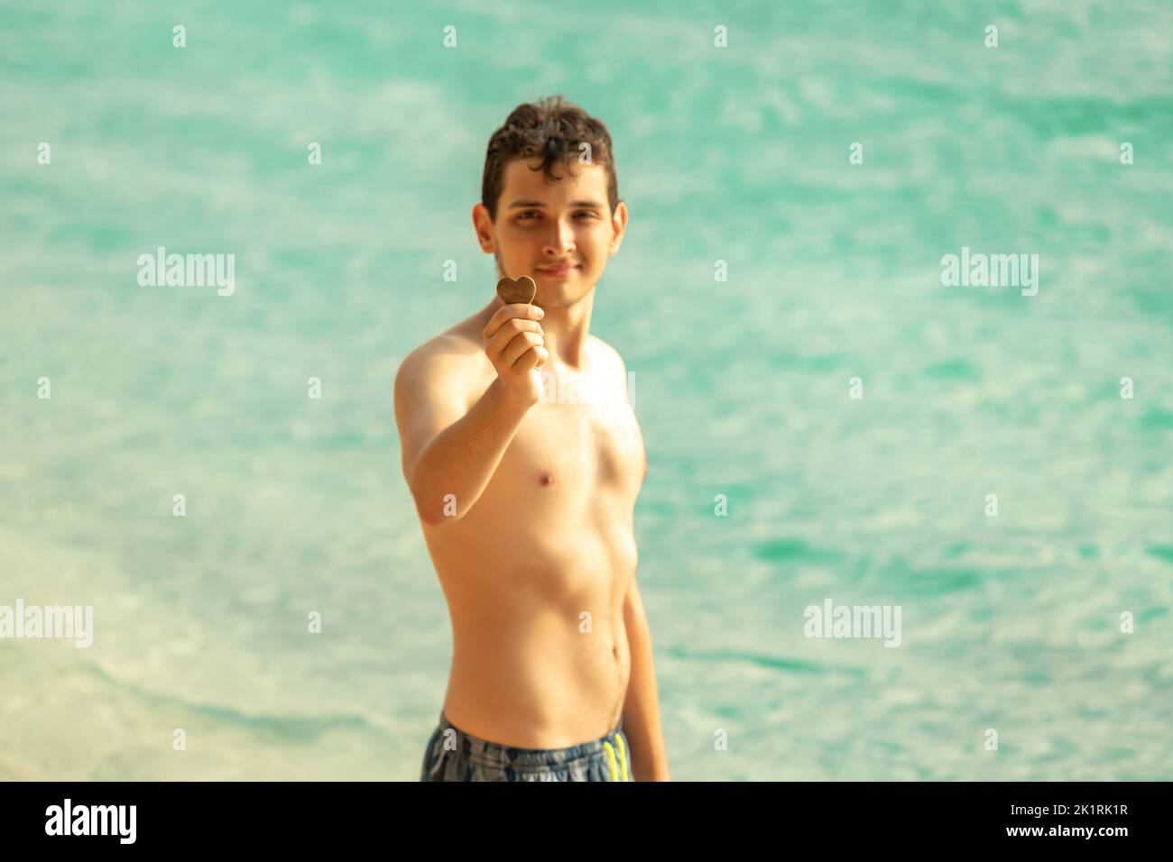 The boy on the beach near the sea with a stone like the heart in his hand Stock Photo