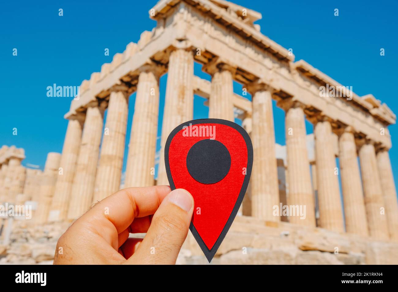 closeup of the hand of a man holding a red marker pointing the remains of the famous Parthenon, in the Acropolis of Athens, Greece Stock Photo