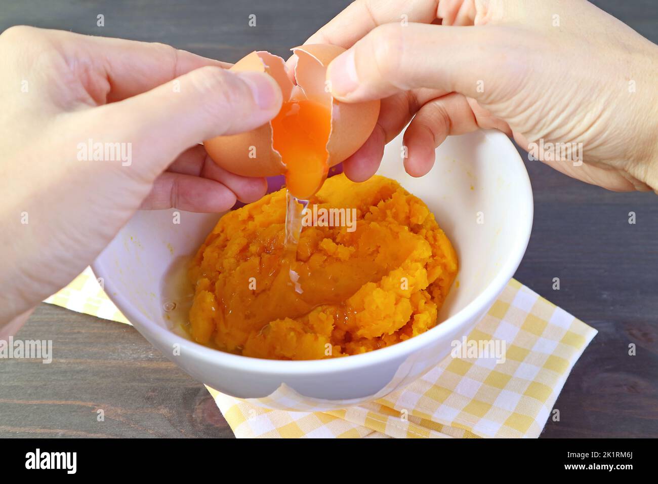 Hand Breaking an Raw Egg on Pumpkin Puree Bowl for Pumpkin Pie Filling