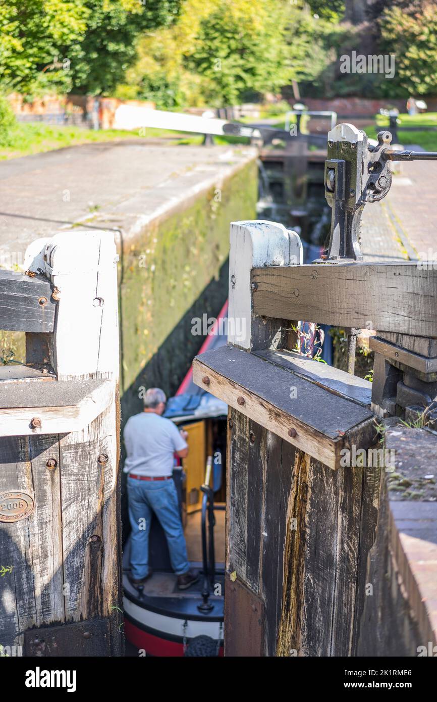 Top view of lock gates on a canal lock closing, as a boat and man have just entered the lock. Stock Photo
