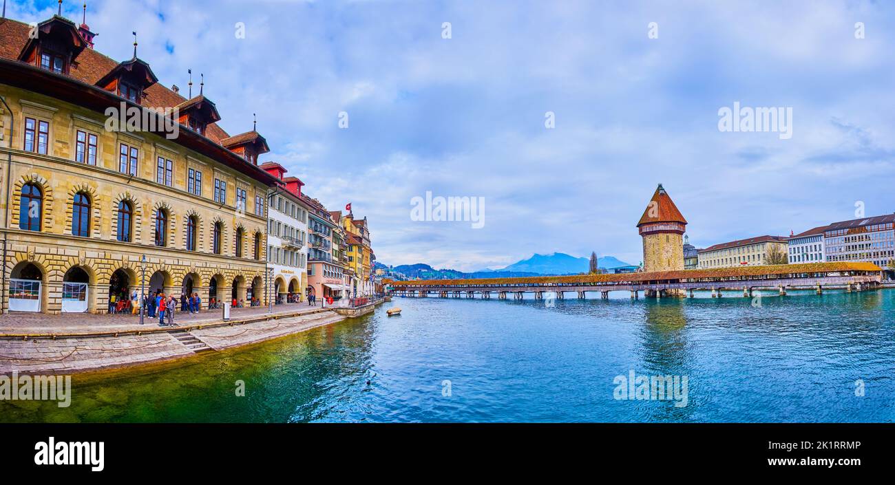 LUCERNE, SWITZERLAND - MARCH 30, 2022: Panorama of medieval Lucerne with stunning buildings, Wasserturm tower and wooden bridge Kapellbrucke across ri Stock Photo