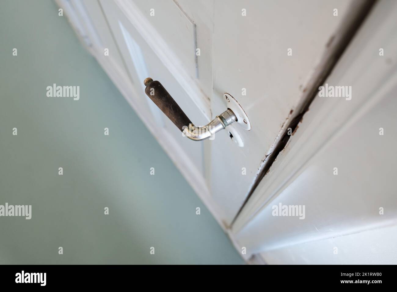 Old doorknob on a white wooden door, indoors. Close-up. Top view. Stock Photo