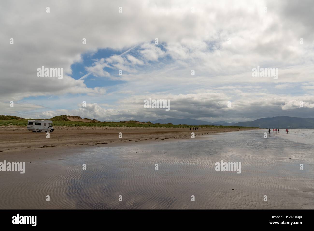 Inch Strand, Ireland - 5 August, 2022: motor home driving along the endless sandy beach at inch Strand in Dingle bay at low tide Stock Photo