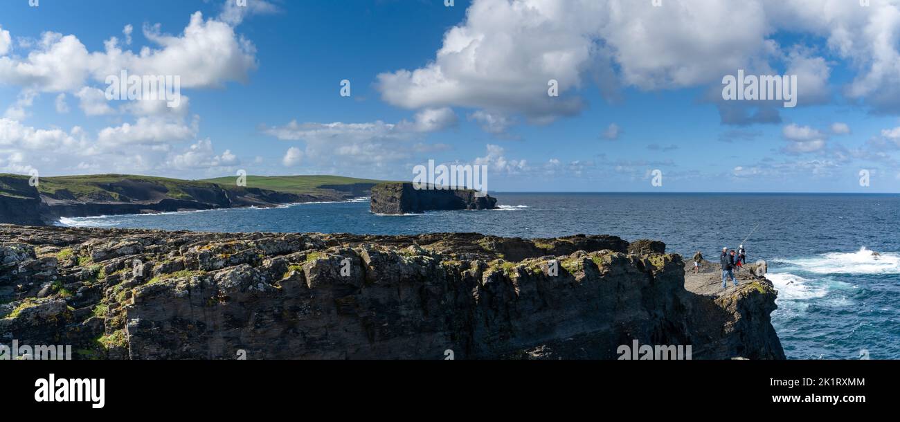 Kilkee, Ireland - 4 August, 2022: panorama landscape of the wild Kilkee Cliffs with daring fishermen on the cliff edge Stock Photo