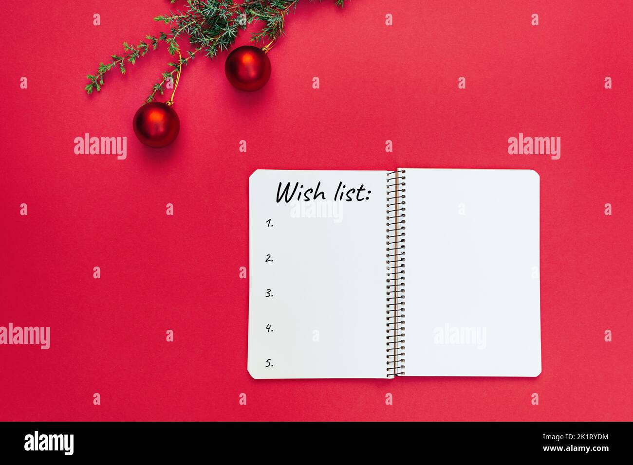 Wish list. Open blank spiral notebook for writing list of dreams and goals. Christmas tree branch with decorations on trendy red background. Copy space text, to-do list. Planning 2023. Minimal style. Stock Photo