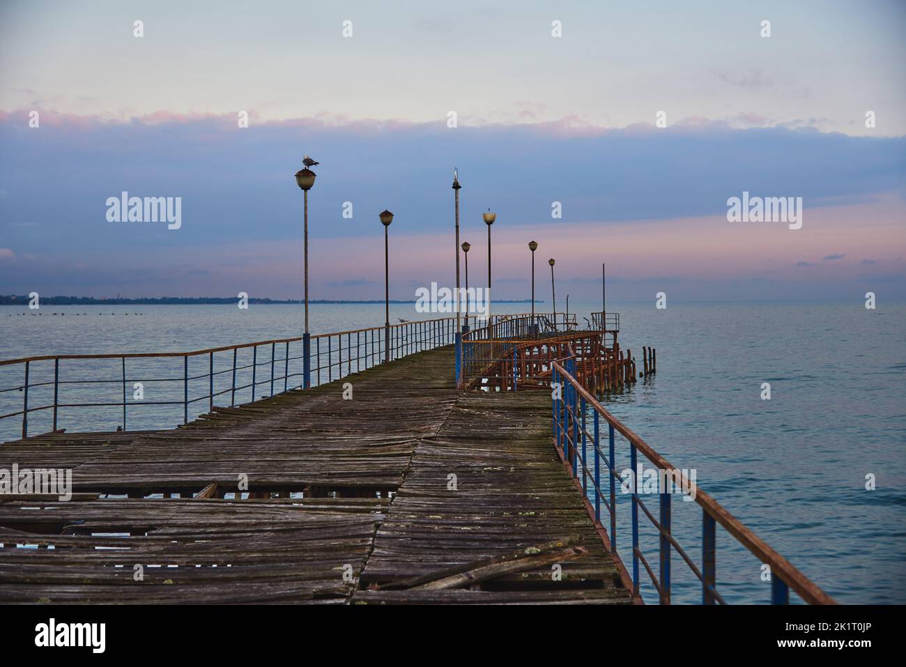 A pier stretching far into the sea against the backdrop of a beautiful sunset. Stock Photo