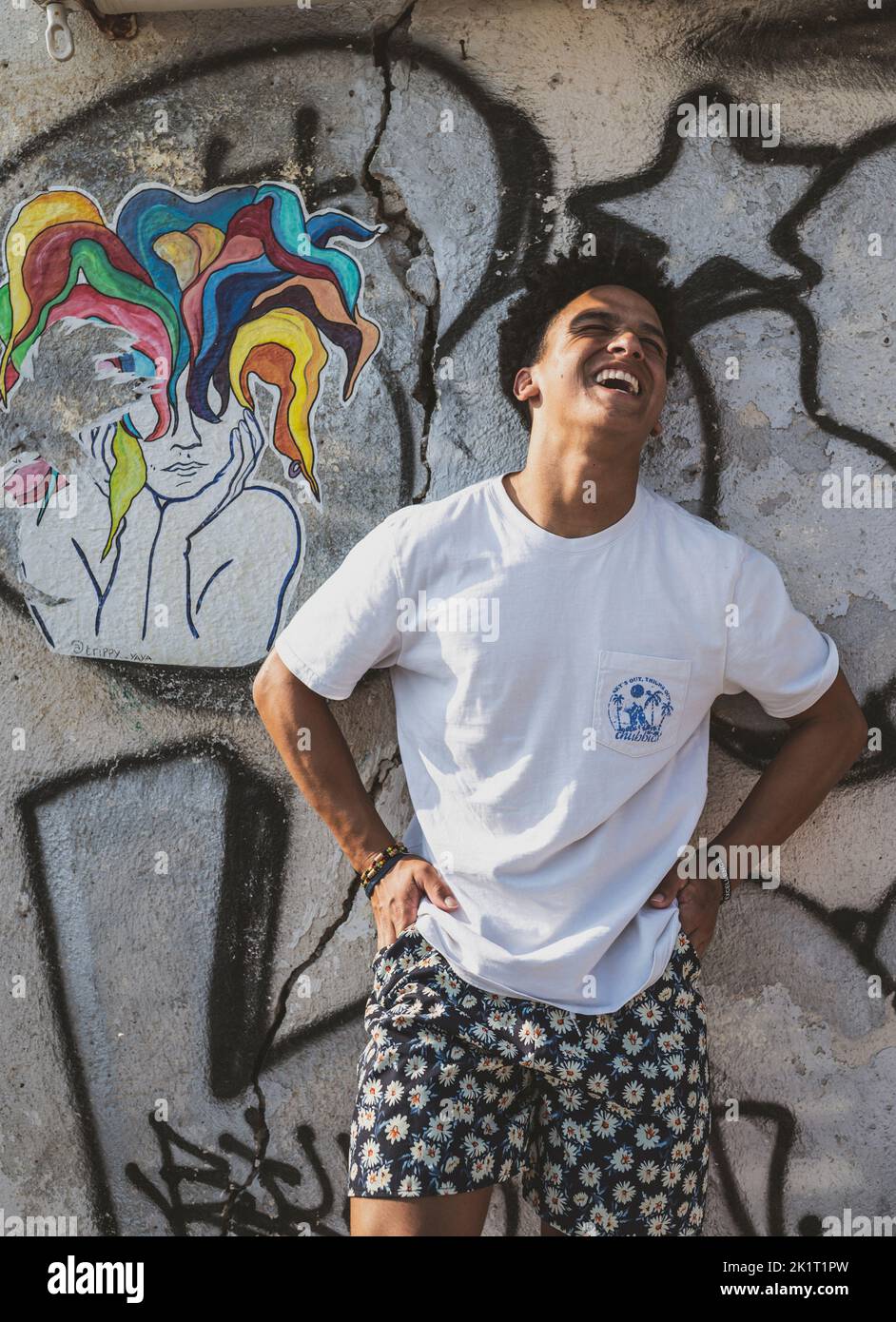 A handsome teenager leaned against graffiti wall in Santorini while traveling in Greece in summer Stock Photo