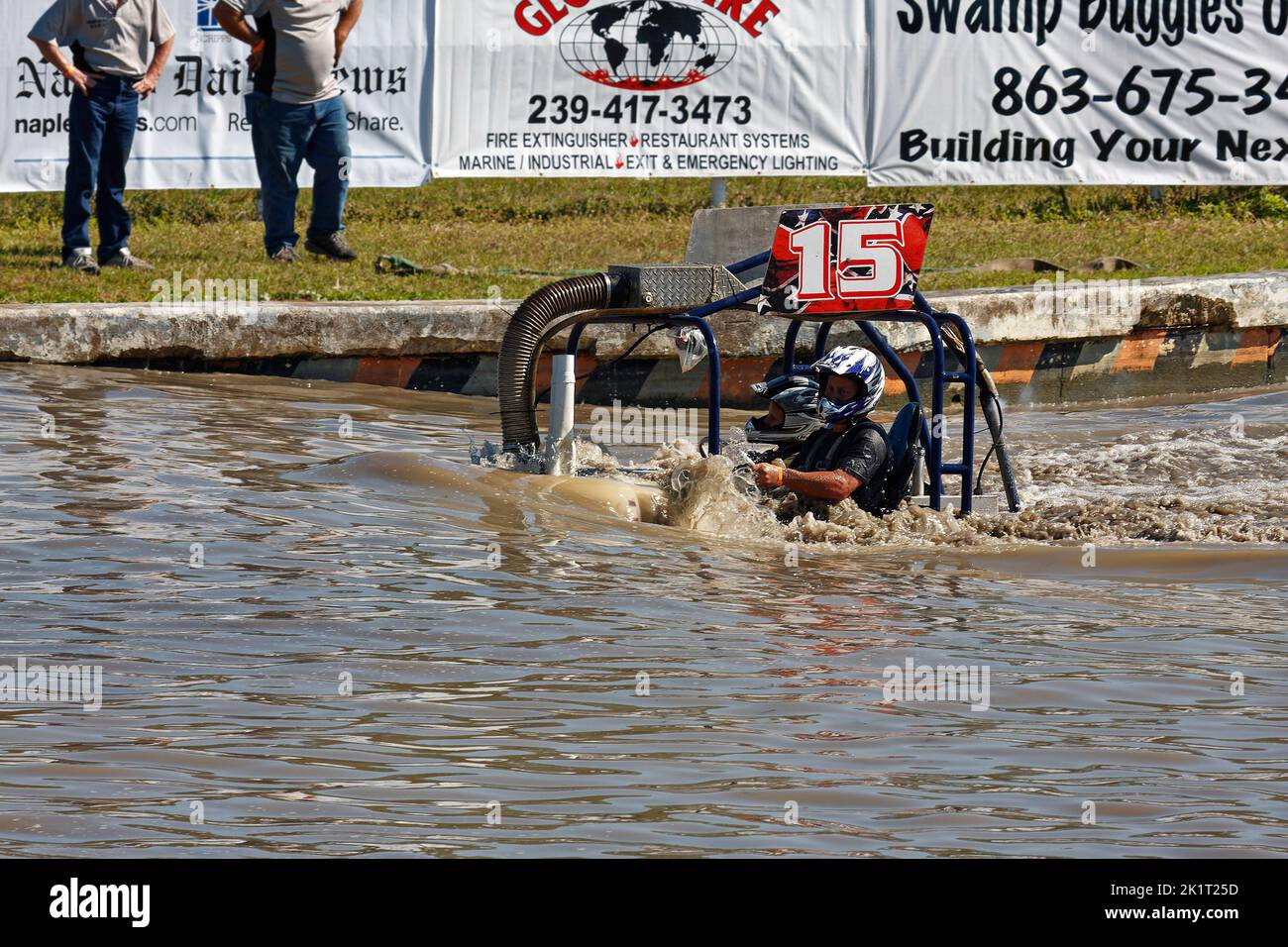 swamp buggy moving through water, action, half submerged, jeep style, vehicle sport, close-up, man, woman, helmets, advertising banners, Florida Sport Stock Photo