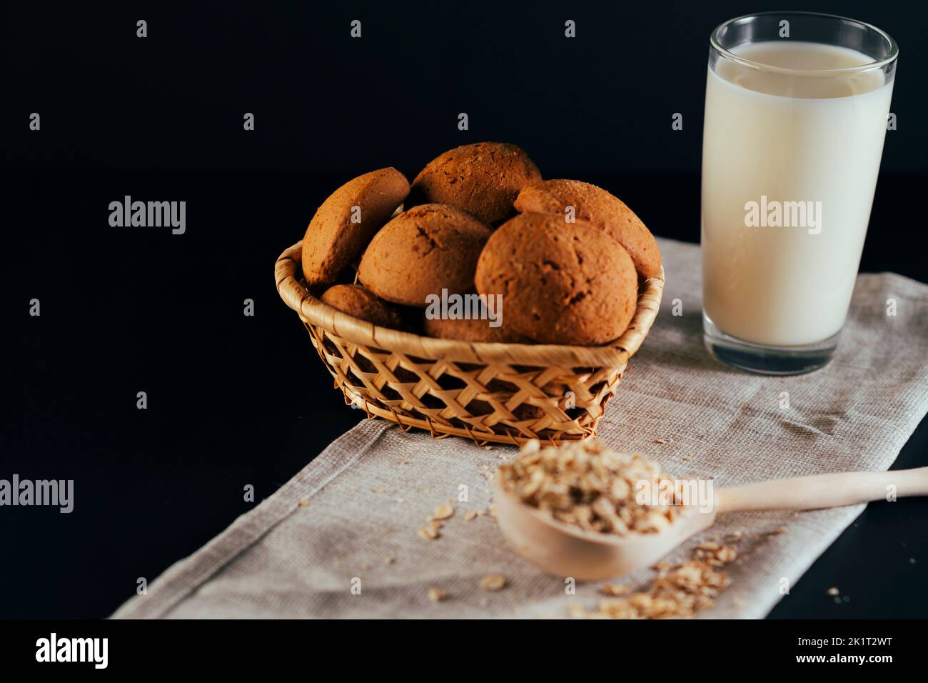 Oatmeal cookies with a glass of milk on a napkin on a black background. The concept of a healthy breakfast Stock Photo