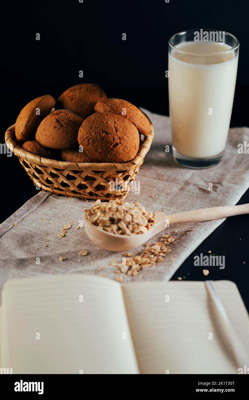 Oatmeal cookies with a glass of milk on a napkin on a black background. The concept of a healthy breakfast Stock Photo
