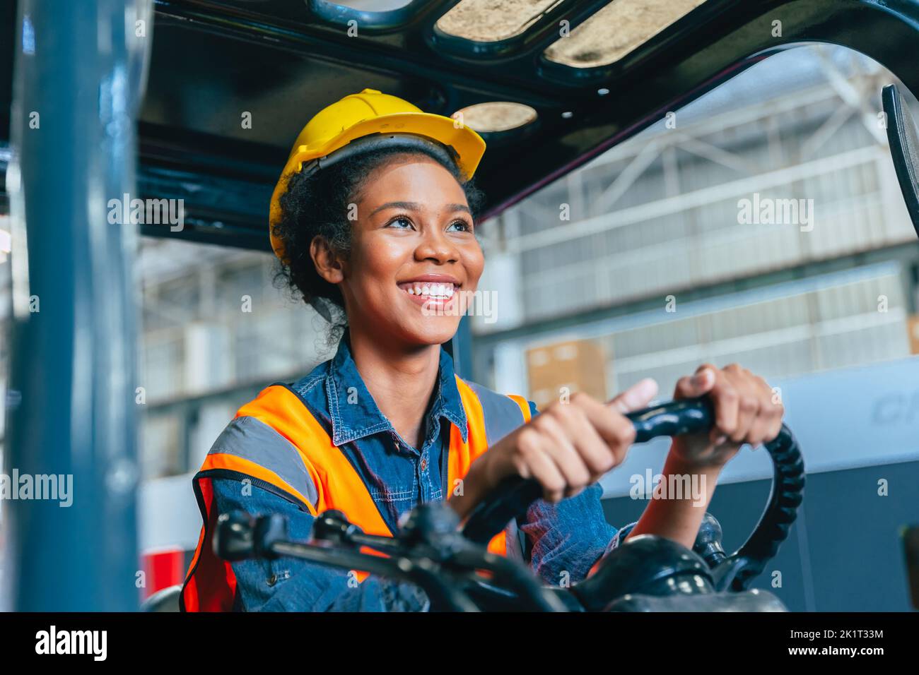 Women labor worker at forklift driver happy smile enjoy working in industry factory logistic shipping warehouse. Stock Photo