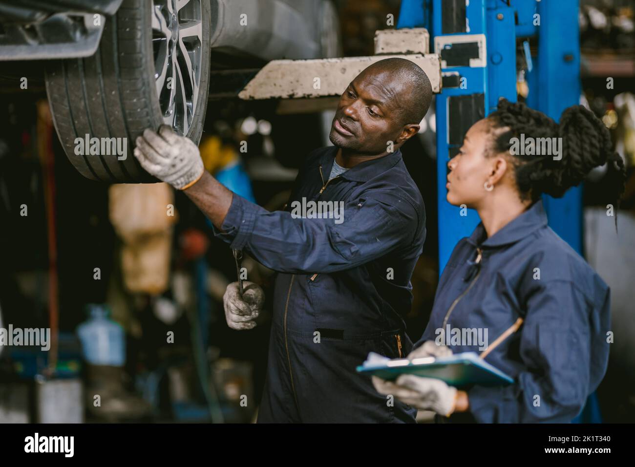Auto garage worker Black African working together to fix service car vahicle wheel support together Stock Photo