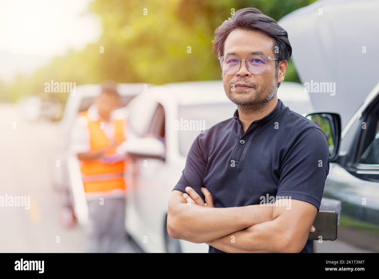 smart asian adult man standing smile satisfied at roadside for car crash problem solving good service from insure team staff Stock Photo
