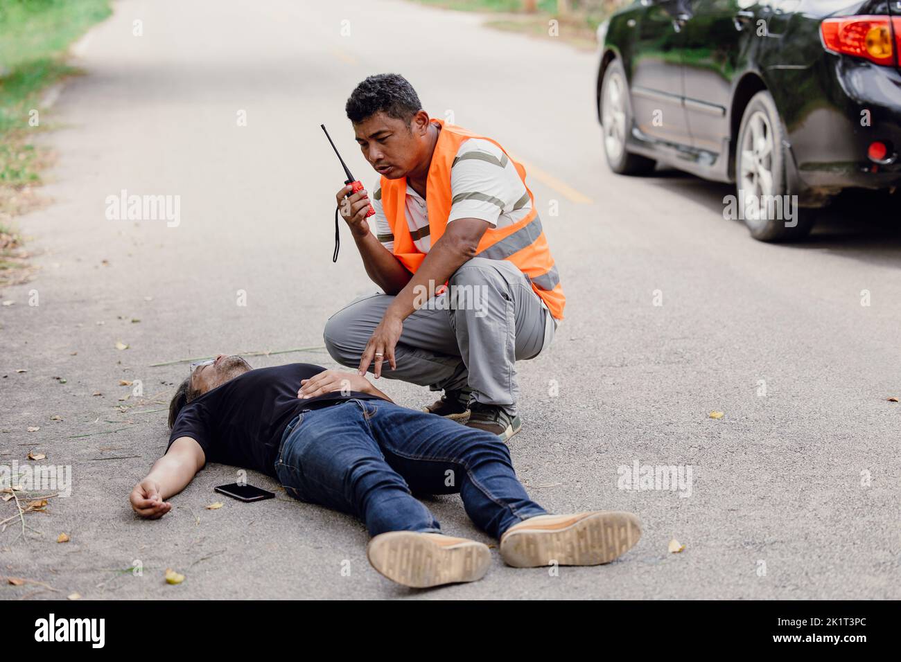 man accident lay down unconscious on the road hit by car during playing phone emergency team staff radio for help Stock Photo