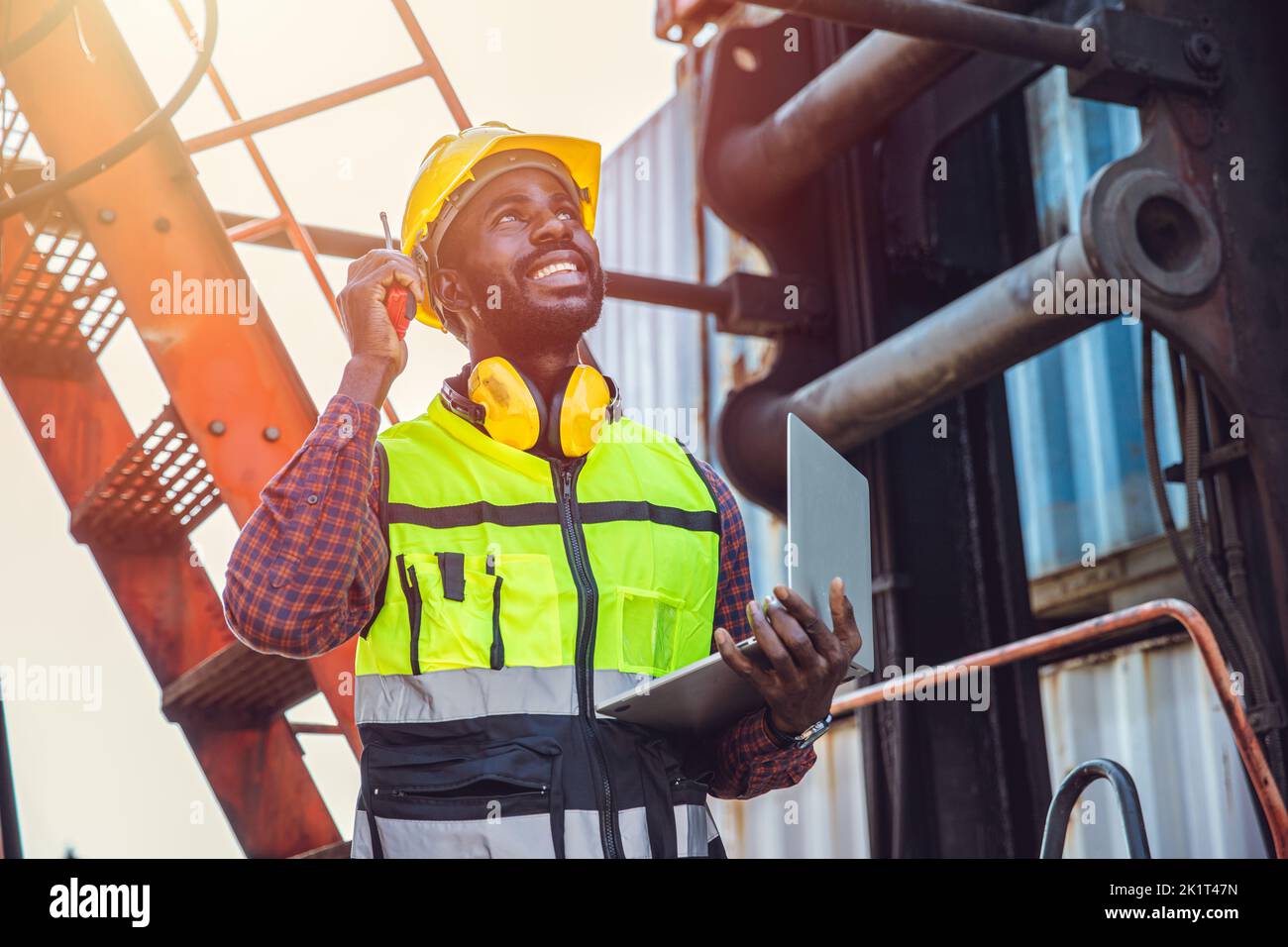Black African male worker working in port cargo radio control loading container in logistic industry. Stock Photo