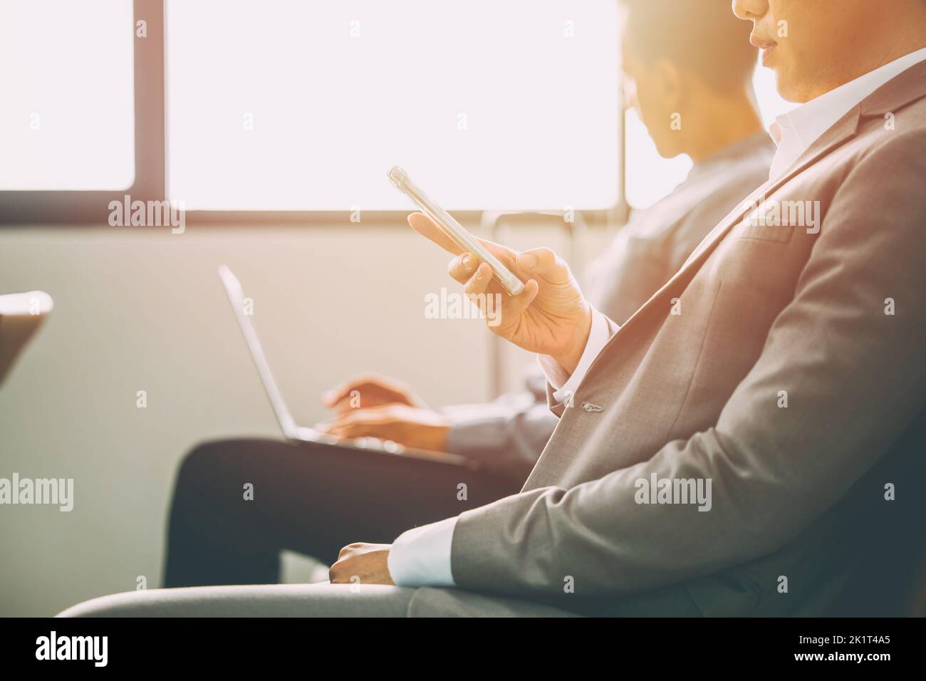 business man with modern people technology concept. two male businessman using laptop computer and smartphone in waiting area. Stock Photo