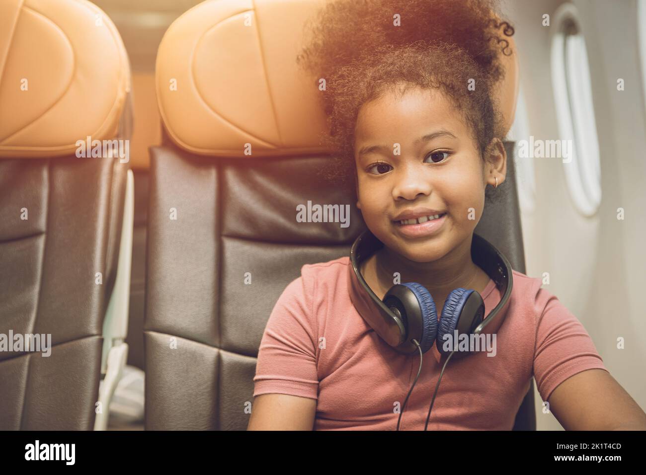 children traveling alone or unaccompanied minor. child girl fly travel sitting alone in flight cabin seat happy smile. Stock Photo