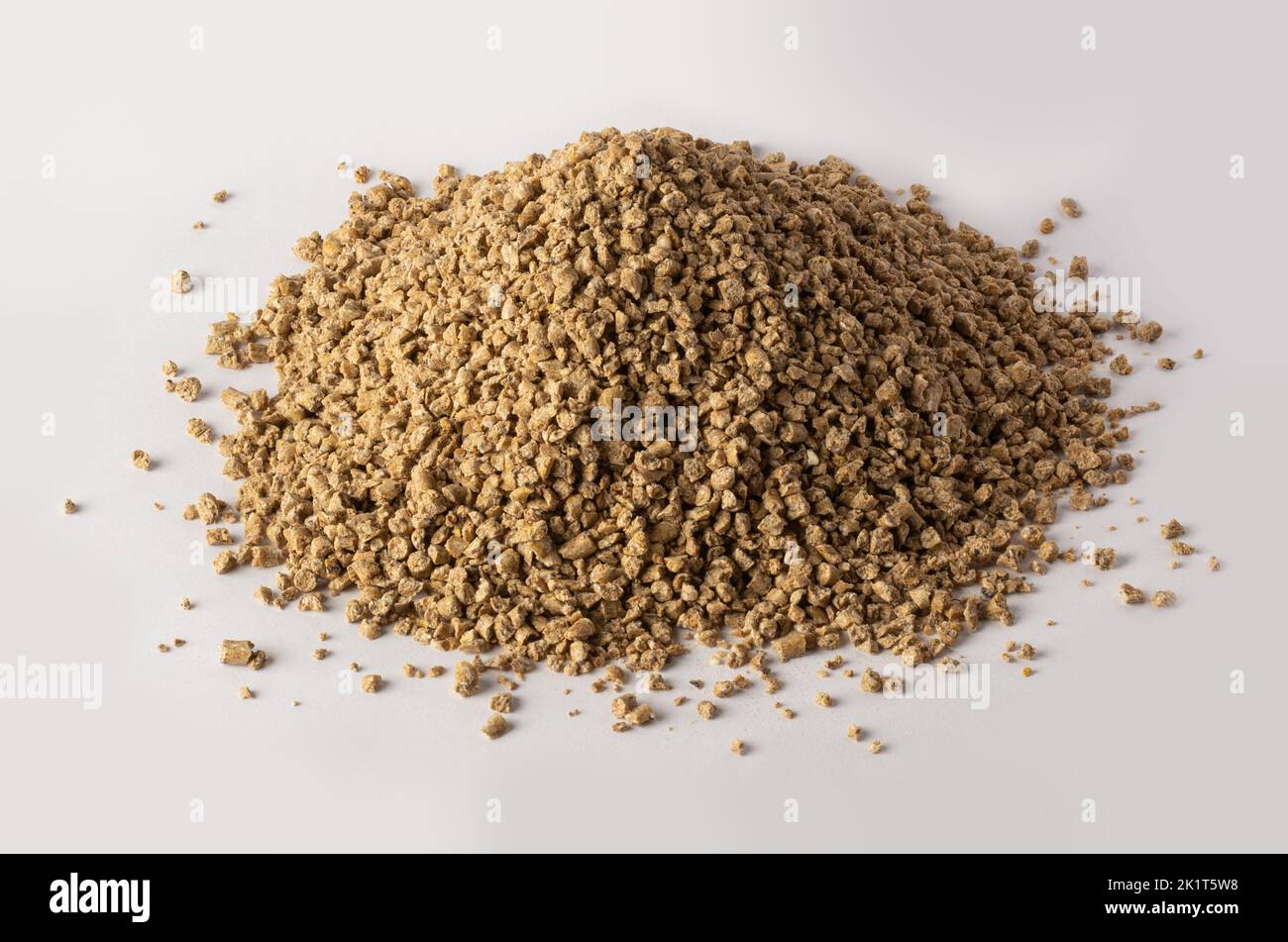 pile of chicken feed crumble, semi-loose variety made from pellets cracked into smaller pieces, isolated on white background Stock Photo