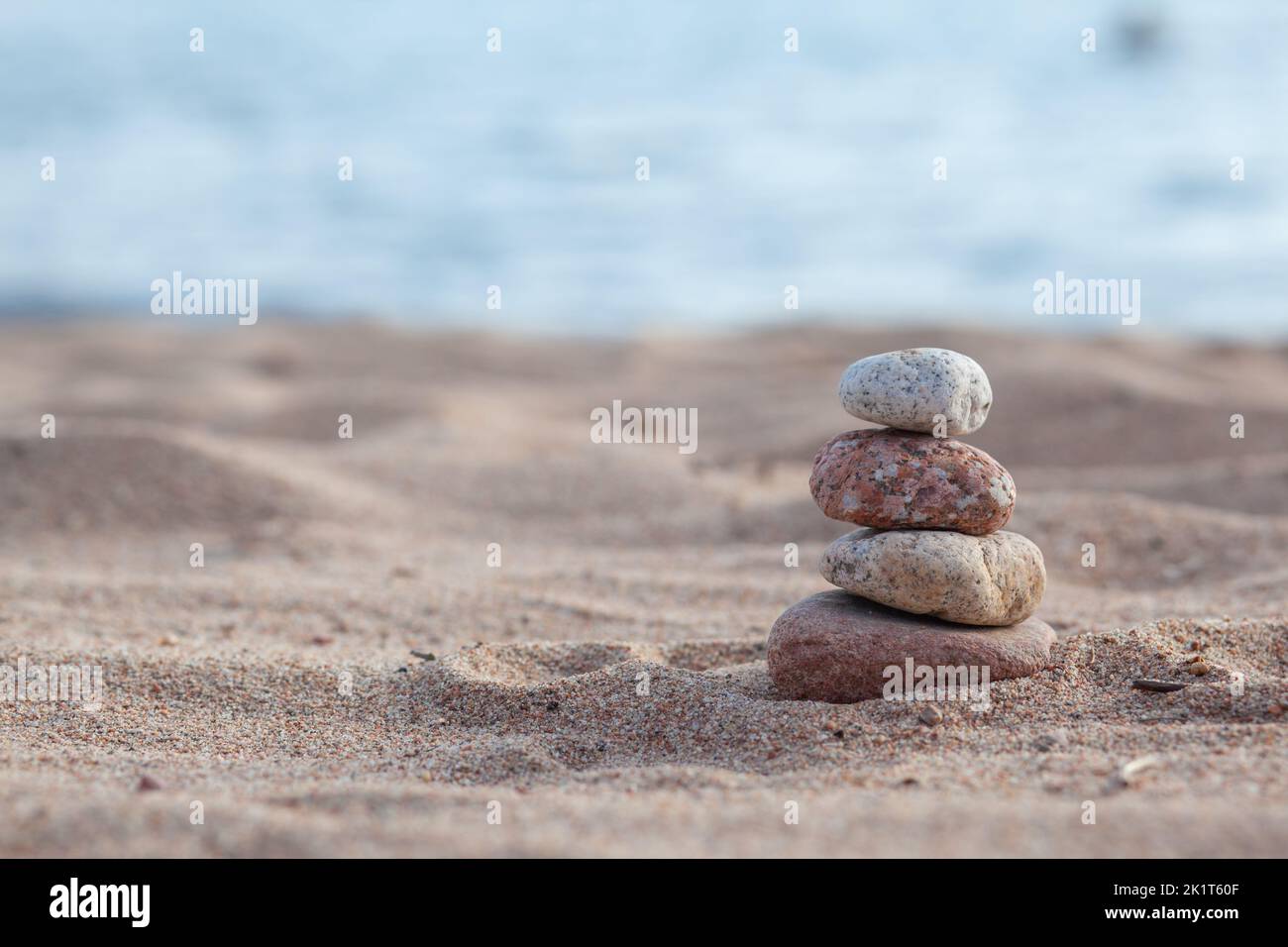 Round stones lie on top of each other in a column on the seashore Stock