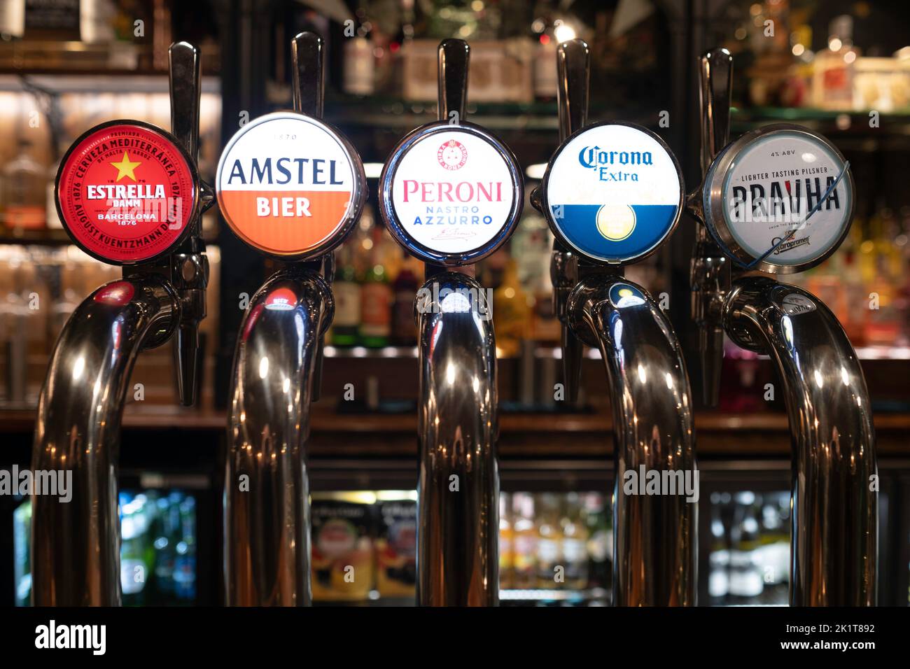 Stainless steel beer taps, craft beer in an English pub, Estrella, Amstel, Peroni, Corona and Pravha signs. Narrow depth of field Stock Photo