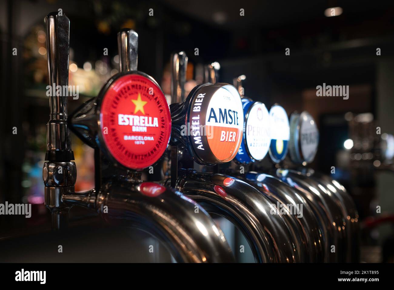 Stainless steel beer taps, craft beer in an English pub, various brands. Focus on 'Amstel Bier' sign. Narrow depth of field, side view Stock Photo