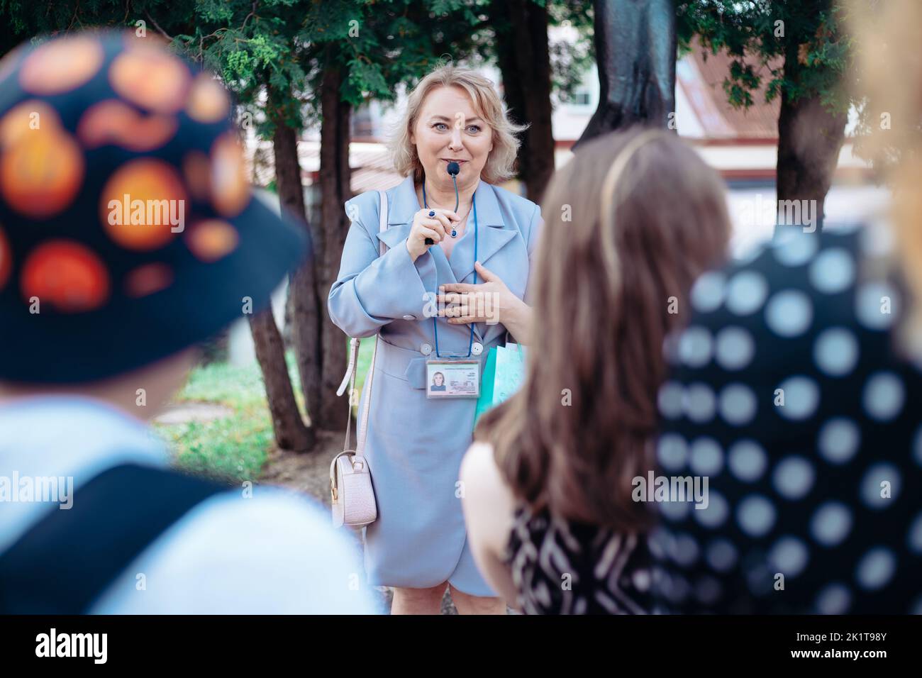 female guide is telling a group of tourists about something Stock Photo ...